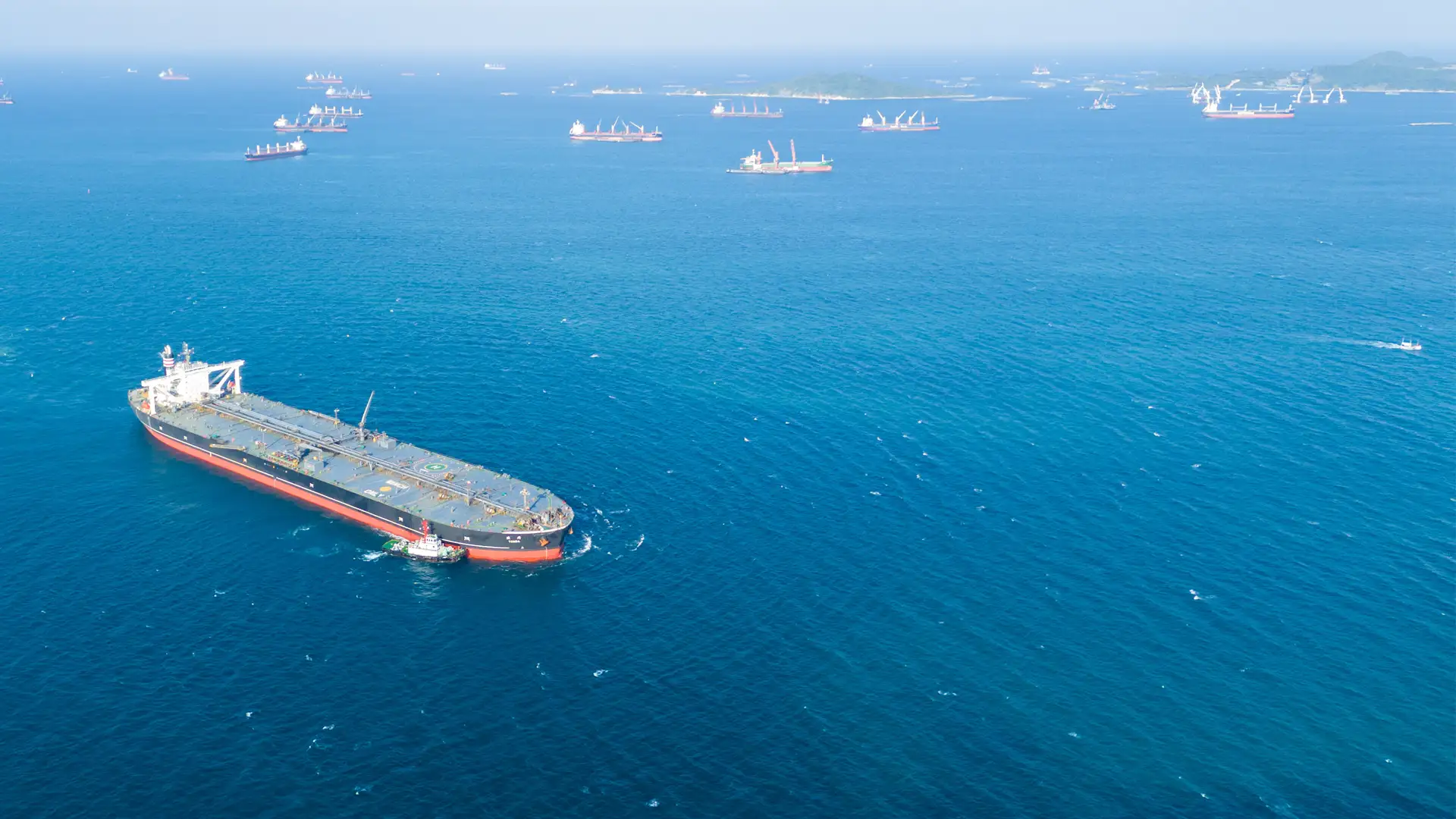 Mehrere Tanker liegen vor einer Küste auf offener See vor Anker; Symbolbild für Energieversorgung, Rohstoffhandel und die Debatte um eine mögliche Energieknappheit.