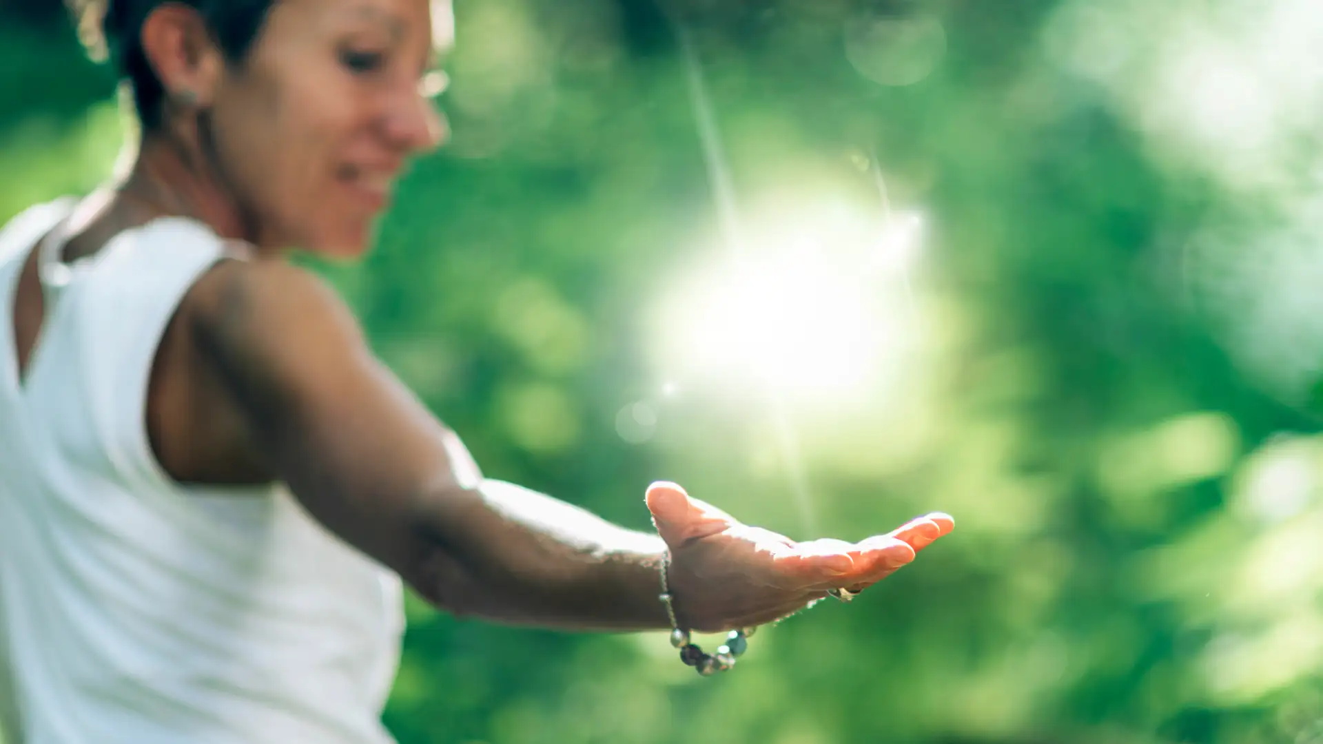 Frau hält die Hand ins Sonnenlicht als Symbol für Lebensenergie, Selbstheilungskräfte, Naturverbundenheit und ganzheitliche Gesundheitsvorsorge.